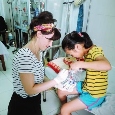Intern from Projects Abroad is seen making a child laugh whilst giving a routine check up whilst on her nursing internship in Vietnam. Projects Abroad female intern is seen making a child laugh during a routine check up on her nursing work experience in Vietnam.